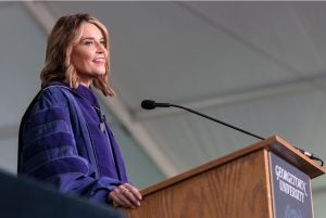 Commencement speaker Savannah Guthrie, wearing academic regalia, standing at a podium