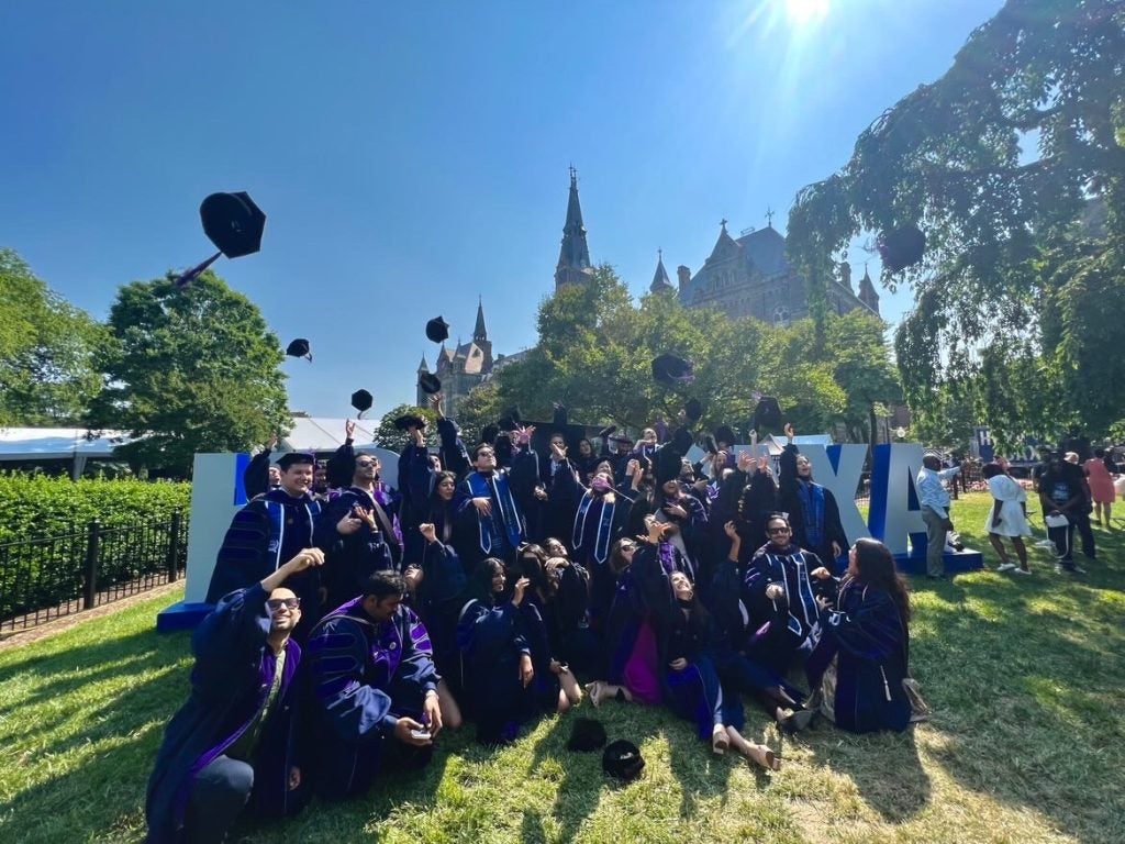 A group of students throwing their graduation caps in the air on the Georgetown campus