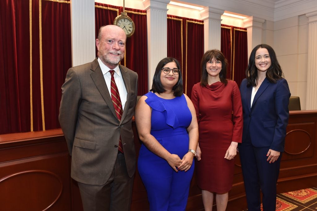 Four people standing in the Georgetown Law Supreme Court Institute moot courtroom