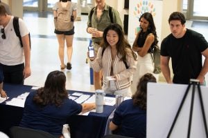 A student displays her phone badge as she checks in for student orientation