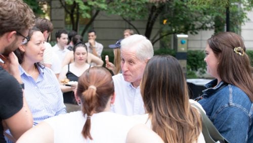 A man speaking to a group of students standing in a circle