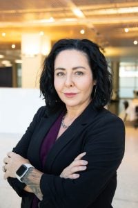 Image of a dark-haired woman wearing a black jacket and purple shirt.