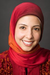 Image of a smiling woman wearing a red and orange head scarf.
