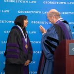 A woman and a man facing each other, wearing academic regalia