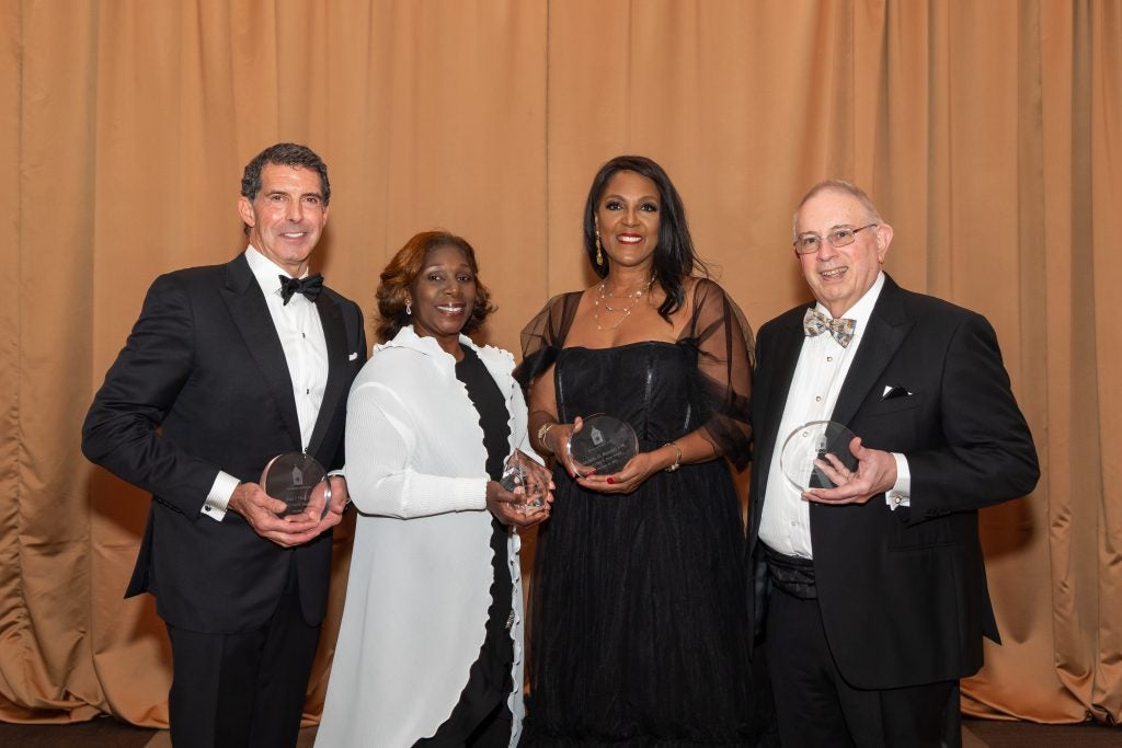 Two men and two women in formal dress, holding award trophies