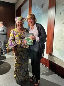 two women standing on a stage and holding a book