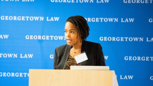 Alicia Plerhoples speaking behind podium with Georgetown Law Backdrop