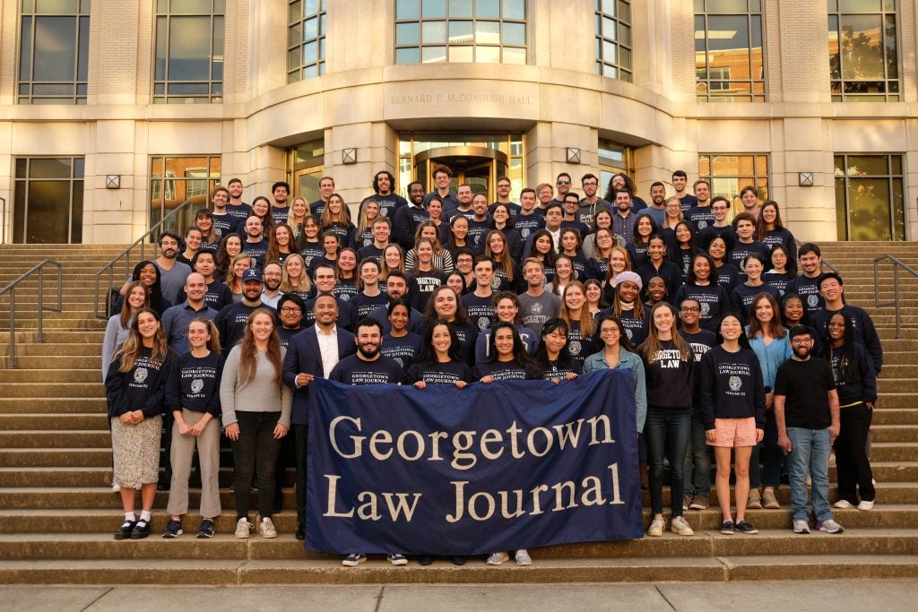 A large group of students on the steps of McDonough Hall, holding a banner reading "Georgetown Law Journal"