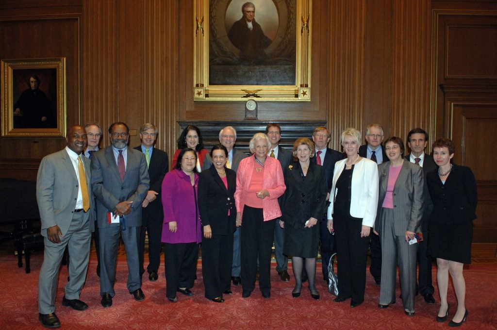 A large group of people standing together at a reception hosted at the Supreme Court. Standing at center is former Justice Sandra Day O'Connor.