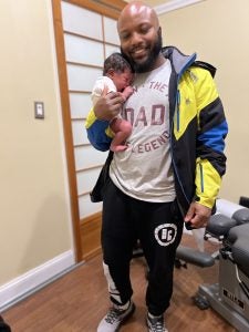 A man wearing a Tshirt that says "Dad" and holding a young baby