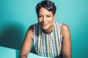 A Black woman wearing a multicolored top and smiling