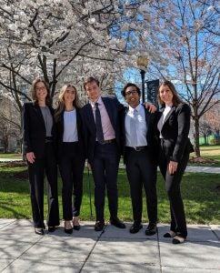 A group of students standing on campus under a blooming cherry tree