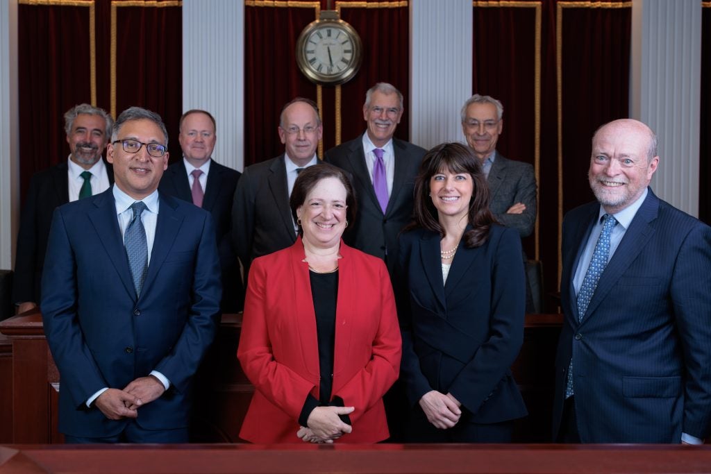 A group of people standing in two rows in a formal Moot Courtroom. Supreme Court Justice Elena Kagan and U.S. Solicitor General Elizabeth Prelogar are in the front row.