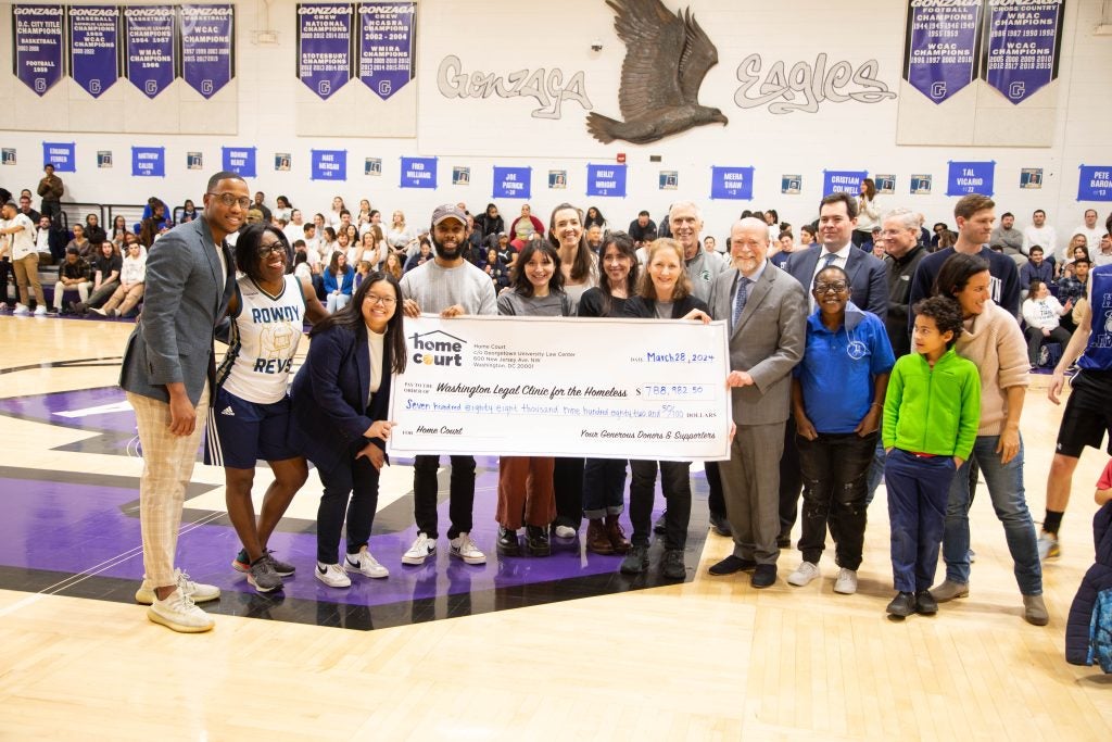 A group of people holding up a large check representing the proceeds of the Home Court fundrasier