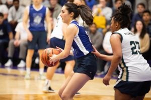 A ponytailed basketball player with a basketball in her hand