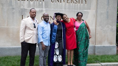 A graduate and loved ones pose for a picture on the Georgetown Law campus.