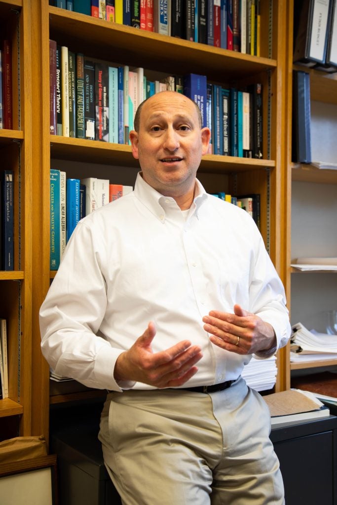 A man in a white shirt standing in front of a bookcase