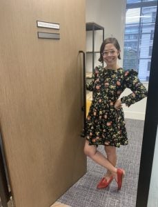 a woman in a floral dress standing in an office doorway