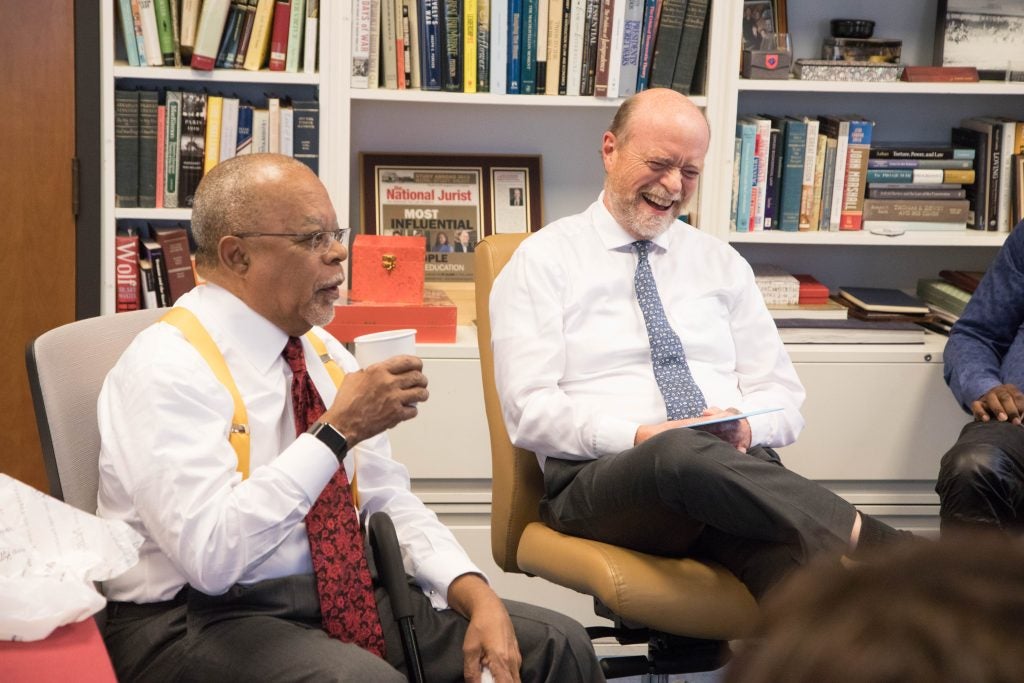 Two men sitting together in an office setting. One is laughing.