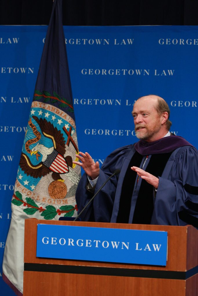 A man in academic robes speaking at a podium at Georgetown Law