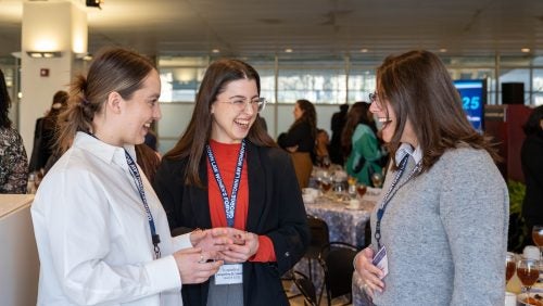 A candid photo of three guests speaking to each other.