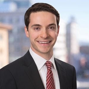 A headshot of a smiling man with dark hair