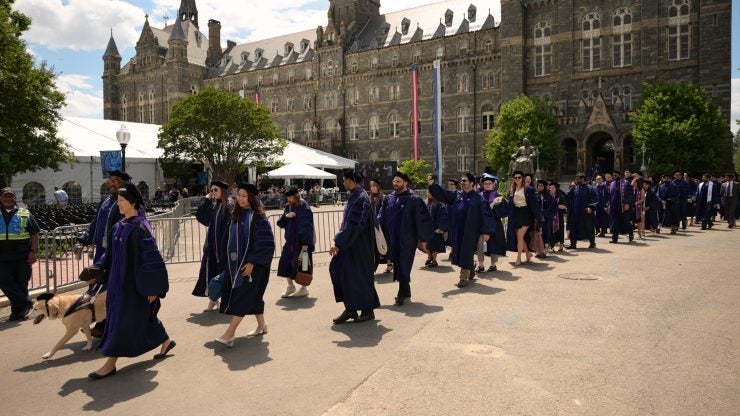 A line of students wearing academic regalia on the Georgetown University campus