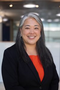 Frances Walters headshot in a orange top and black blazer.