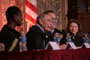 Four professors dressed in judicial robes, sitting at a table together