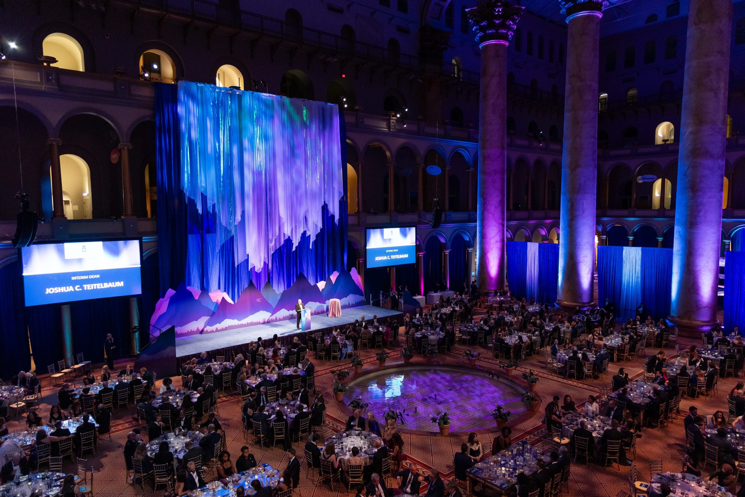 An aerial view of the tables and stage at the National Building Museum, decorated in a northern lights theme.
