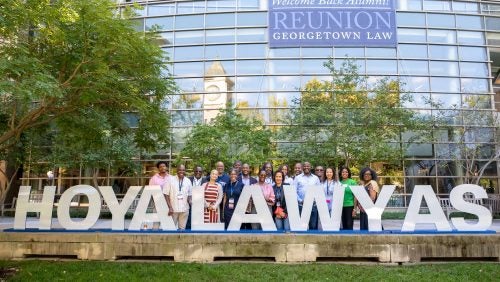 Brunch attendees pose with a 'Hoya Lawyas' sign on campus.