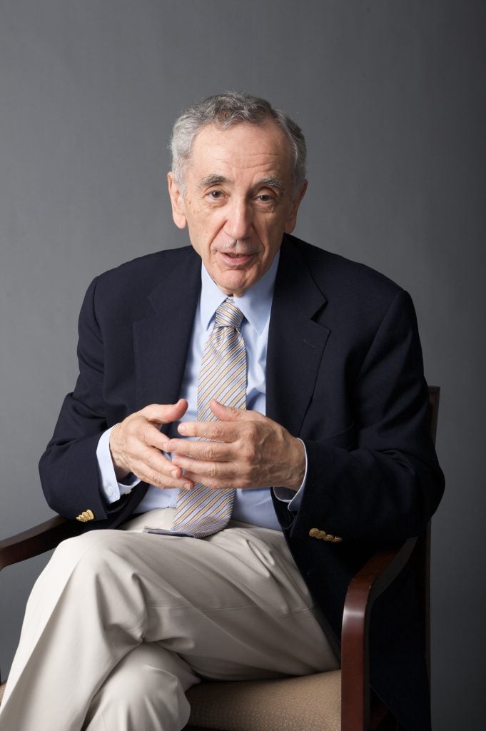 A gray-haired man in a jacket and tie