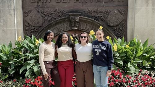 Four 1L students and West Point women graduates pose for a photo on the Georgetown Law campus.