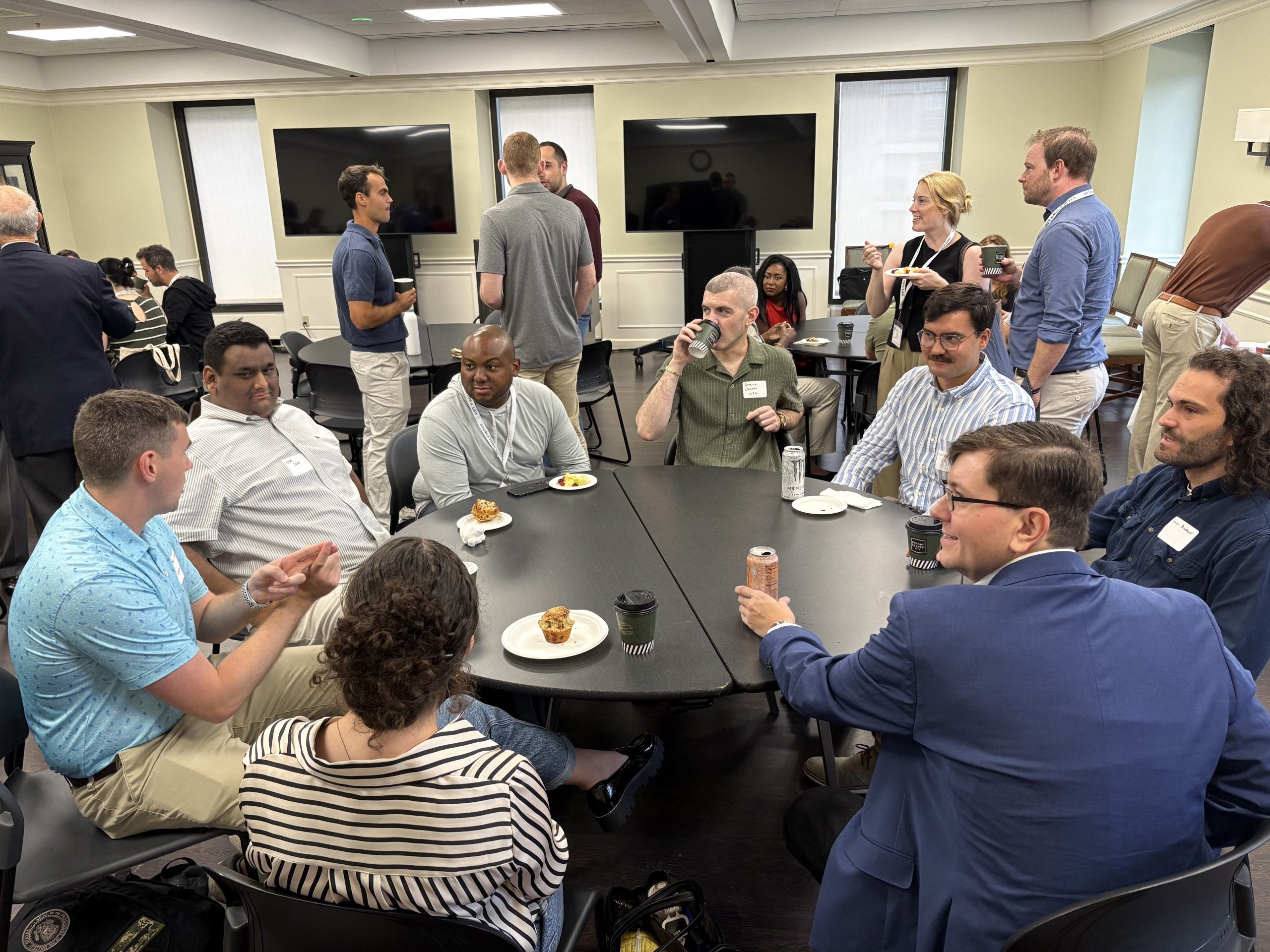Students sit at a round table, talking and eating breakfast.