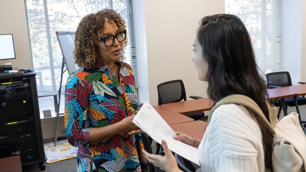 A professor in a colorful dress speaking with a student