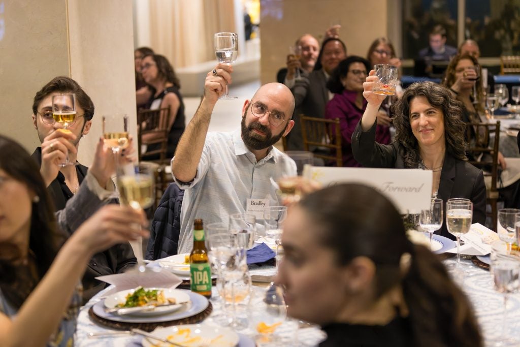A group of people sitting and raising their glasses in a toast