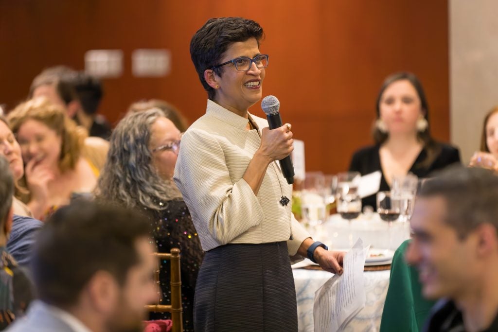 a woman standing and speaking into a microphone