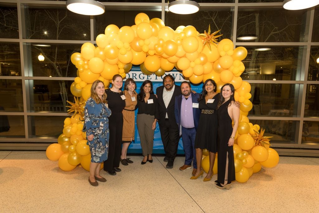 A group of people standing before a balloon arch