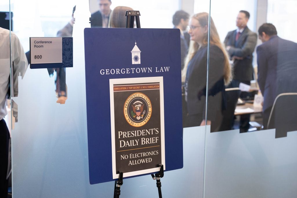 A printed sign outside a conference room states: "President's Daily Brief" and "No Electronics Allowed" 