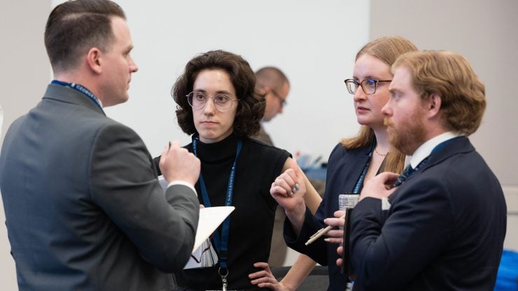 Four students stand together in a conference while they deliberate.