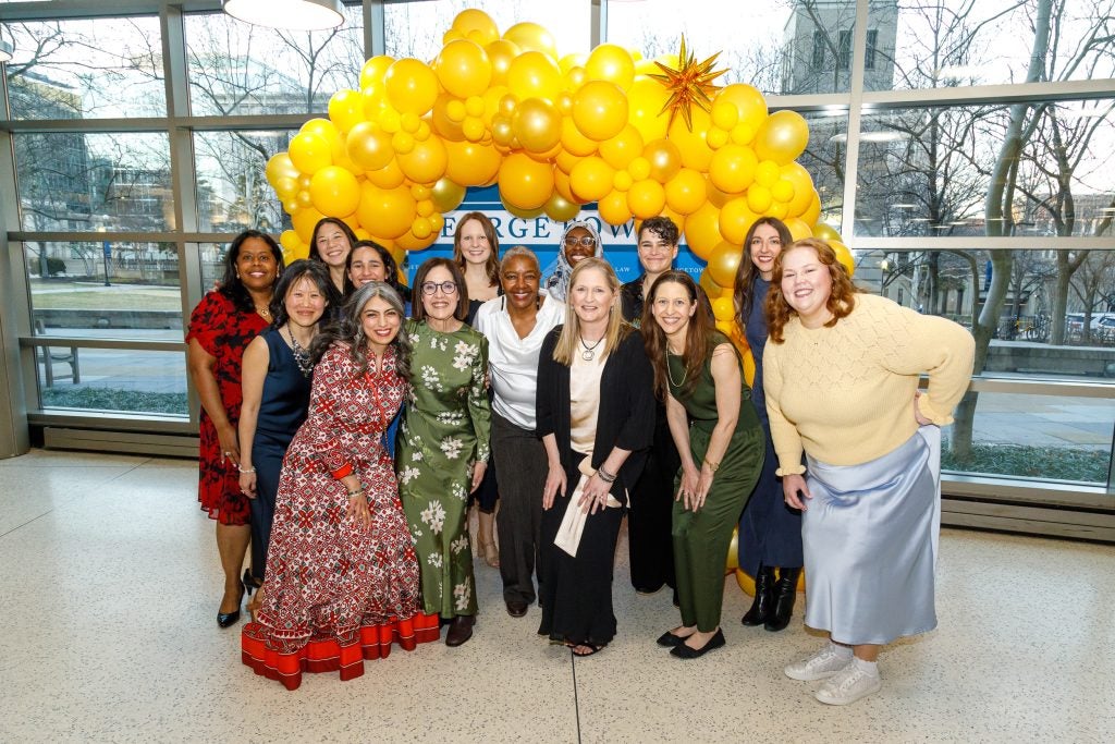 A group of people standing and smiling in front of a balloon arch