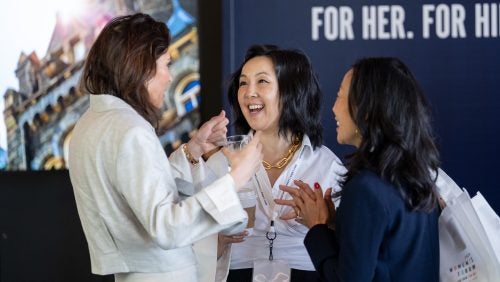 Three attendees stand and animatedly talk to each other.
