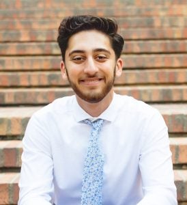 Headshot of Hamza, wearing a white shirt and blue tie, smiling
