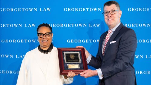 Two people smile and hold a plaque
