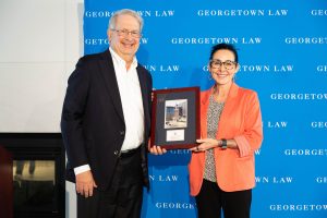 Two people smile and hold a plaque 