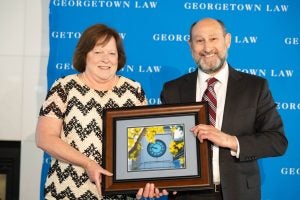 Two people smile and hold a plaque