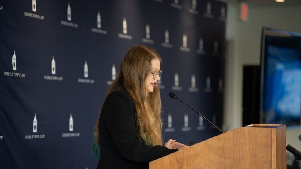 A woman stands at the podium and addresses the audience.