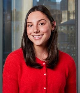 Headshot of Kate, wearing a red cardigan and smiling