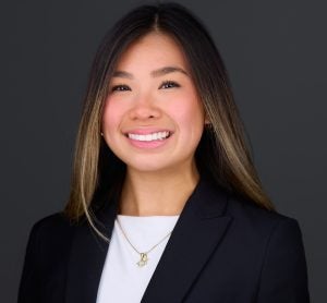 Headshot of Hannah smiling, wearing a blazer and white shirt.