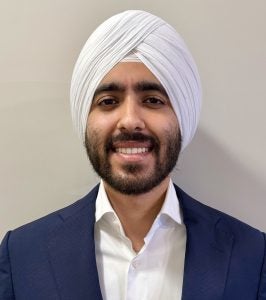 Headshot of Arjun, wearing a navy jacket and white shirt, smiling